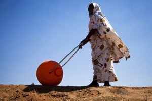 在北达尔富尔的法希尔，一名妇女正在使用河马水碾压机，这是一种方便有效地搬运水的设备。“河马滚轮”的滚筒容量很大(通常为75升)，使妇女和儿童不必每天花大量时间为家庭取水。非洲联盟-联合国达尔富尔混合行动(达尔富尔混合行动)在达尔富尔地区分发了大约3万辆这种滚筒。图片来源:United Nations Photo / Flickr